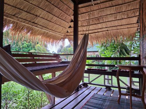 a hammock hanging from a wooden porch with a table and a table at Sense Asia in Haad Tian