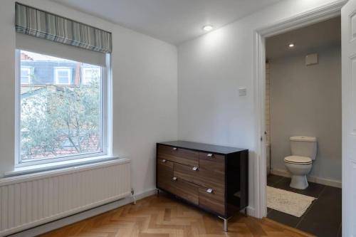 a bathroom with a dresser and a toilet and a window at 1 bed Townhouse in Battersea close to River Thames in London