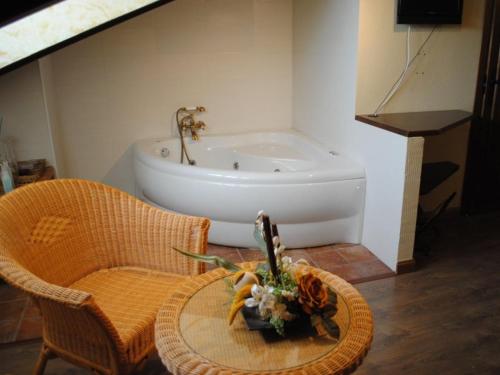baño con bañera y mesa con flores en Hospedería Tía María, en Casillas