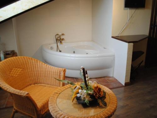 a bathroom with a bath tub and a table with flowers at Hospedería Tía María in Casillas