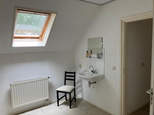 a bathroom with a sink and a chair and a window at Borger appartement in centrum dorp. in Borger