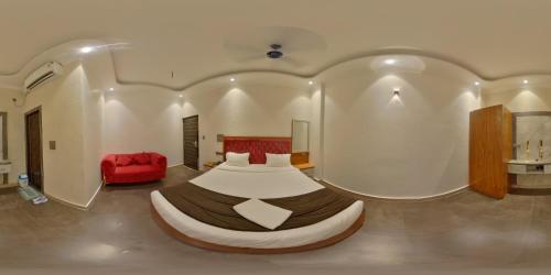 a bedroom with a large bed and a red chair at Green Mapple in Muzaffarpur