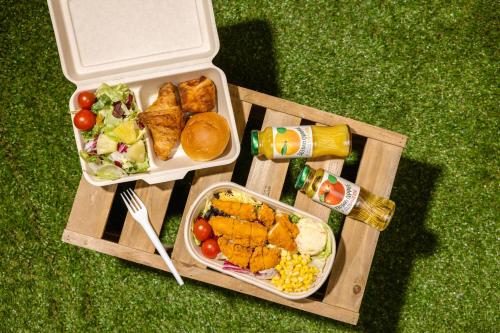 einen Picknicktisch mit zwei Tabletts Essen auf dem Gras in der Unterkunft Kensington Resort Chungju in Chungju