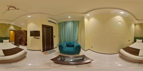 a hotel room with two beds and a blue chair at Green Mapple in Muzaffarpur