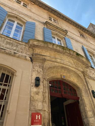ein altes Gebäude mit blauen Fensterläden in der Unterkunft Hôtel du Musée in Arles