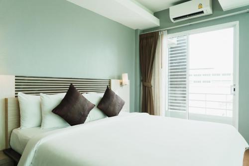 a bedroom with a white bed and a window at Green Hotel and Resort in Khon Kaen
