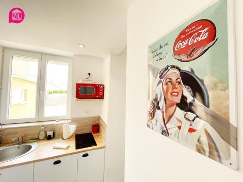 uma casa de banho com um poster de coca cola na parede em Le Nouaillé by iZiLi - Calme et confort - Parking em Poitiers