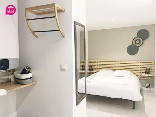 1 dormitorio con espejo y 1 cama blanca en Le Nouaillé by iZiLi - Calme et confort - Parking, en Poitiers