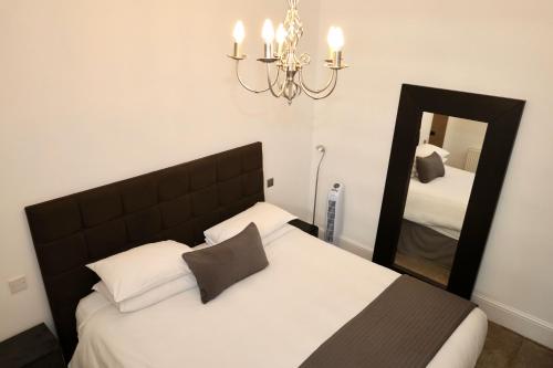 a bedroom with a bed with a mirror and a chandelier at Brighton Inn Boutique Guest Accommodation in Brighton & Hove