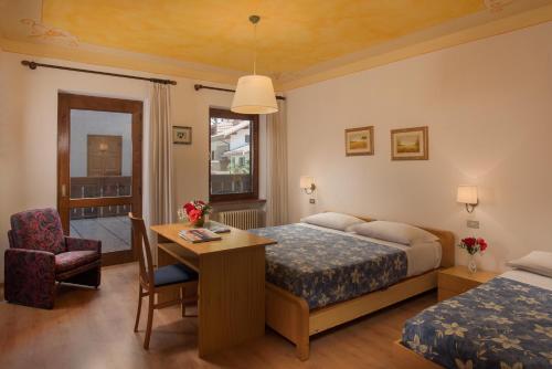 um quarto de hotel com uma cama, uma secretária e uma cadeira em Hotel Centrale em Alleghe