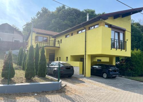 a yellow house with two cars parked in front of it at Stunning 3 bedroom Villa in Moneasa in Moneasa