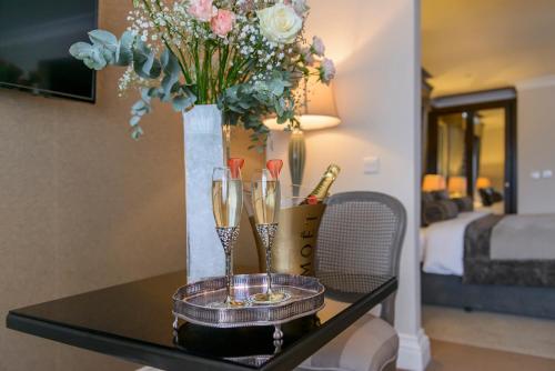 a table with two champagne glasses and a vase with flowers at Killarney Oaks Hotel in Killarney