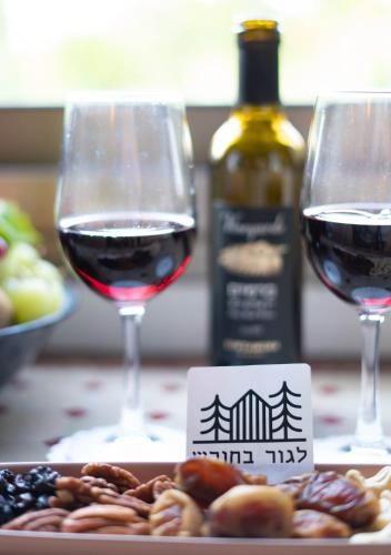 two glasses of red wine next to a plate of food at Live in the woods in Mikhmannim