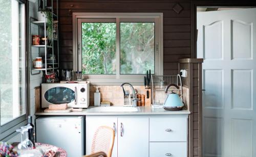 a kitchen with a counter with a microwave and a window at Live in the woods in Mikhmannim