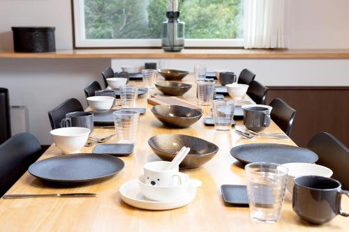 a long wooden table with plates and bowls on it at Villa Noël Hakone Fuji Sauna&Open Air Bath in Hakone
