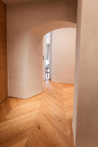 an empty room with a wooden floor and an archway at H5 Grauer Bär Studios & More in Innsbruck
