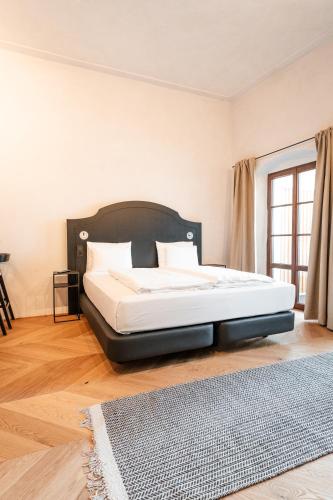a bedroom with a large bed with a black headboard at H5 Grauer Bär Studios & More in Innsbruck