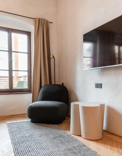 a living room with a black chair and a table at H5 Grauer Bär Studios & More in Innsbruck