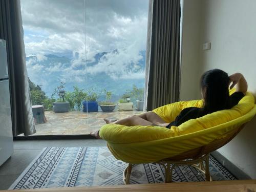 a woman sitting in a chair looking out a window at Bungalow view fanxipang 1579 Sa Pa in Sa Pa