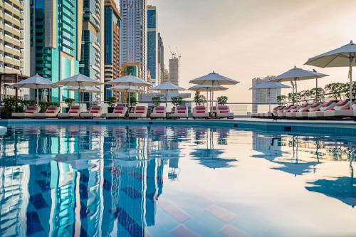 una piscina con sillas y sombrillas en una ciudad en Towers Rotana - Dubai, en Dubái