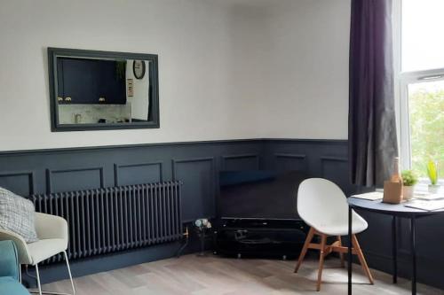 een woonkamer met een tv en een tafel en stoelen bij St Davids Central Apartment in Exeter