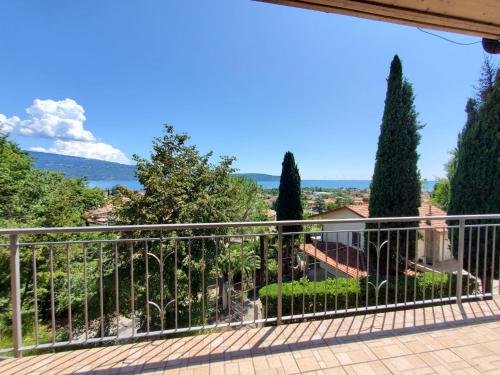 a balcony with a view of trees and the ocean at Garda Sunshine in Toscolano Maderno