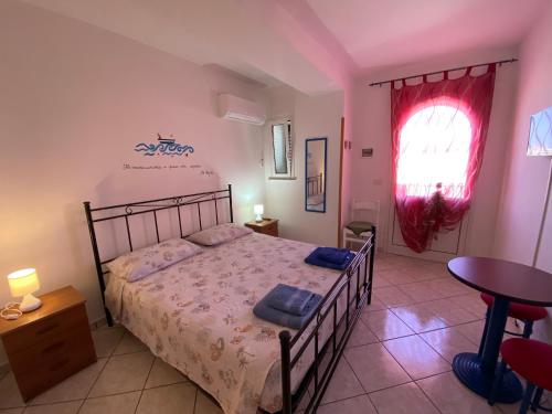 a bedroom with a bed and a table and a window at Lecce Rooms in Castro di Lecce