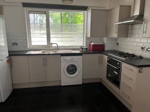 een keuken met een wasmachine en een wastafel bij 3 bedrooms flat Crystal Palace in Londen