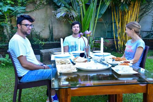 a group of three people sitting around a table with food at The New Crown Hotel in Dambulla