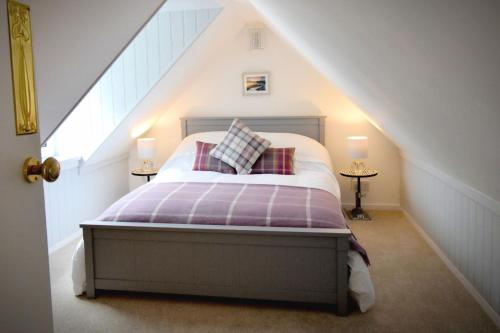 um quarto com uma cama com lençóis e almofadas roxos em Dram Cottage, Findhorn Bay em Forres