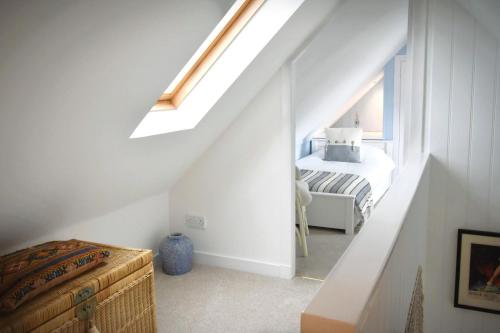 een witte zolderkamer met een bed en een raam bij Dram Cottage, Findhorn Bay in Forres