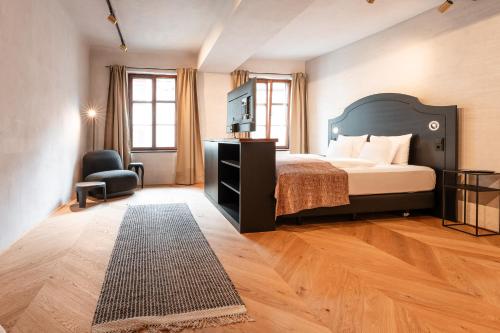 a bedroom with a bed and a chair in a room at H5 Grauer Bär Studios & More in Innsbruck