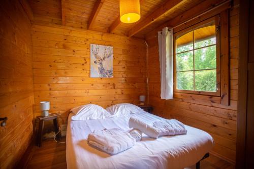 a bedroom with a bed in a log cabin at Camping du Château Vert in Hondainville