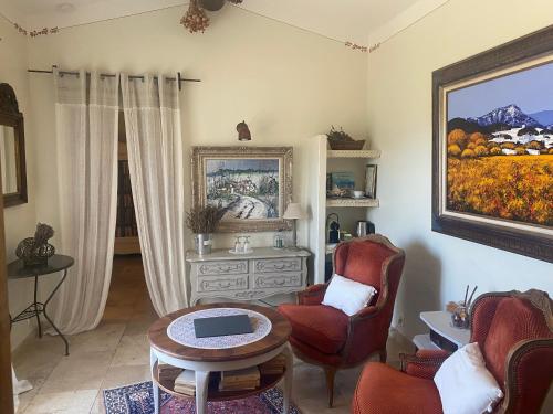 a living room with a table and chairs and a painting at Mas de la Beaume in Gordes