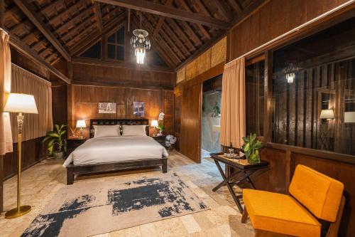 a bedroom with a bed and a table and a chair at The Corduroy Hotel in Canggu