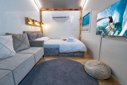 ein Wohnzimmer mit einem Sofa, einem Bett und einem TV in der Unterkunft snow spa caravan in Tefahot