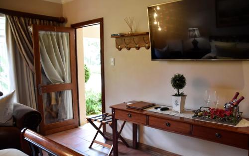 a living room with a table and a television on the wall at LUXURY ROOM @ 4 STAR GUEST HOUSE in Middelburg