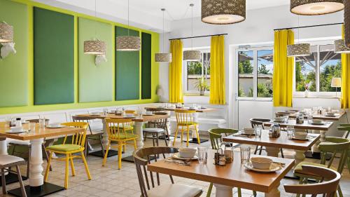 um restaurante com mesas de madeira e paredes e janelas amarelas em Hey Lou Hotel Piding em Piding