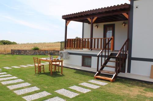 a patio with a table with chairs and a deck at Tinos Otel & Bağ Evi 12 Yaş Üstü in Bozcaada