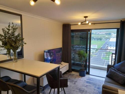 ein Wohnzimmer mit einem Esstisch und einem TV in der Unterkunft Modern Apartment in Chapel Towers (with Inverter) in Kapstadt