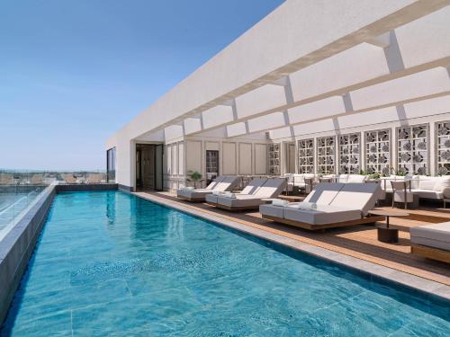 una piscina con sedie a sdraio e un edificio di NYX Esperia Palace Hotel Athens by Leonardo Hotels ad Atene