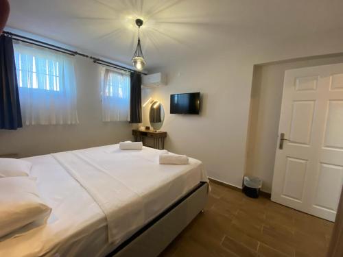 a bedroom with a large white bed and a door at Tinos Otel & Bağ Evi 12 Yaş Üstü in Bozcaada