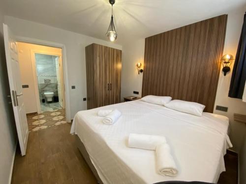 a bedroom with a white bed with two towels on it at Tinos Otel & Bağ Evi 12 Yaş Üstü in Bozcaada