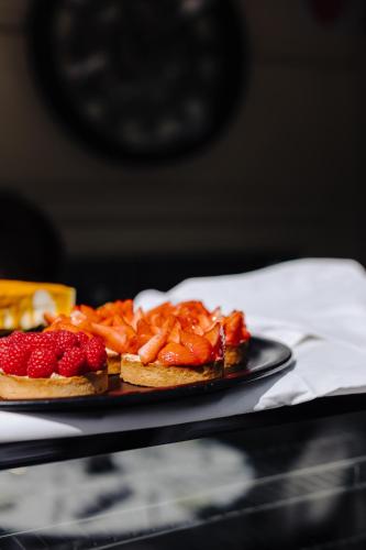 two pizzas with strawberries on a plate on a table at Hôtel & Appartements Monsigny in Nice