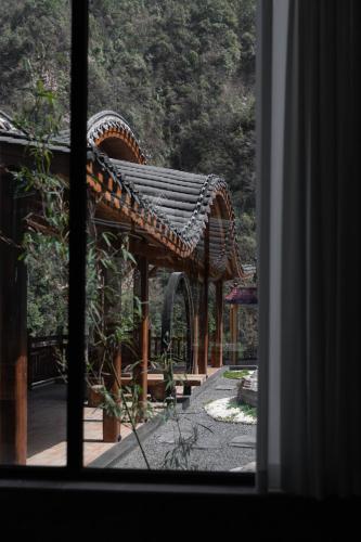 a view of a wooden pavilion through a window at 雾里观阵山 Foggy Valley in Zhangjiajie