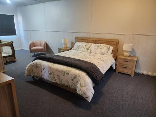 a bedroom with a large bed and a chair at House on Ryan in Broken Hill