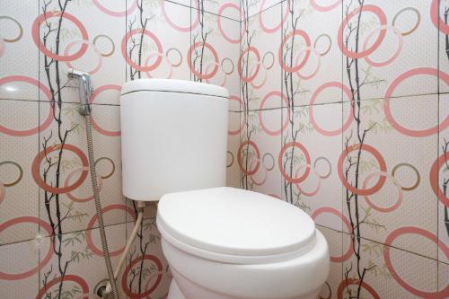 スラカルタにあるRedDoorz near Candi Sukuh Karanganyarの白いトイレ(壁に赤い丸が付いたバスルーム内)