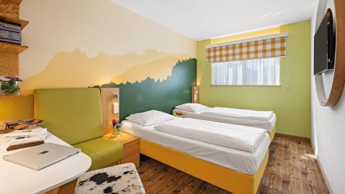 Pokój z 2 łóżkami i biurkiem z laptopem w obiekcie Styles Hotel Piding w mieście Piding