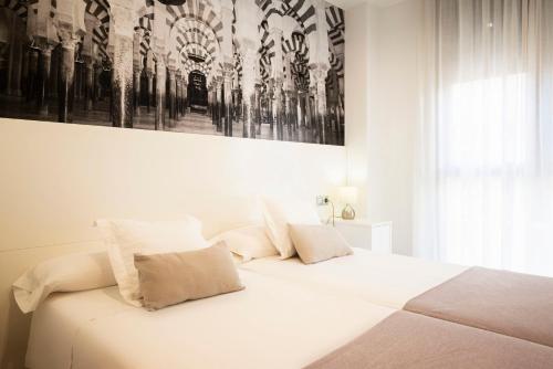a bedroom with a white bed with a picture on the wall at Monteras C&oacute;rdoba Centro in C&oacute;rdoba