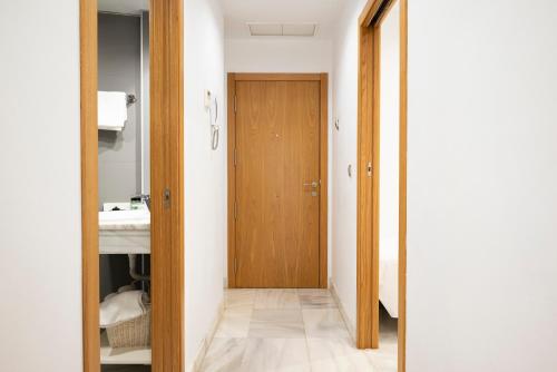 un couloir avec une porte en bois et une salle de bains. dans l'établissement Monteras Córdoba Centro, à Cordoue